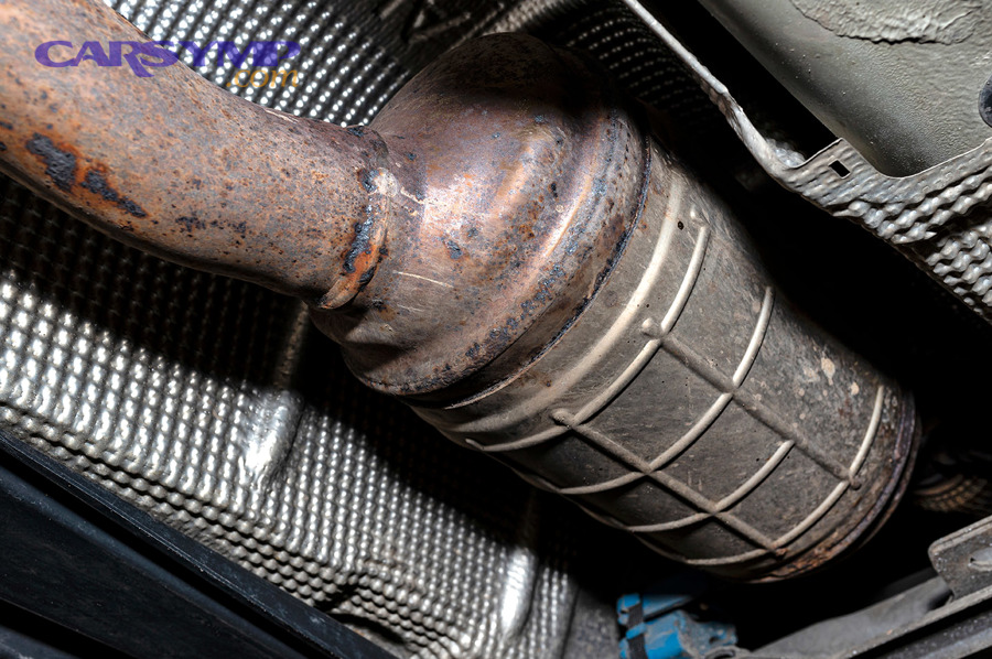DPF canister under vehicle showing rust and heat shielding nearby