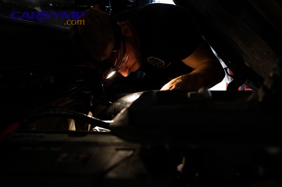 Technician inspecting an engine compartment for oil leaks