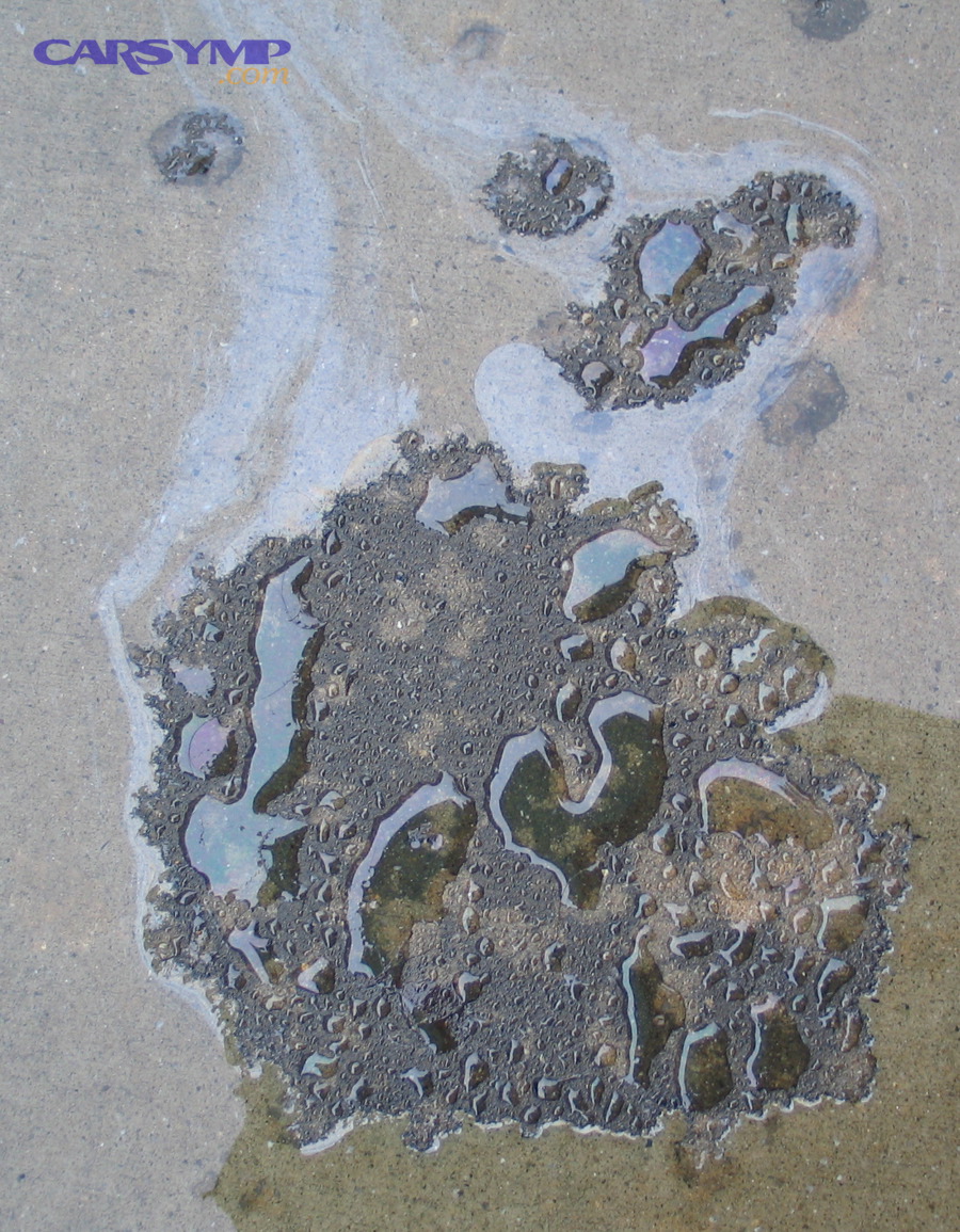 Oil puddle on pavement indicating possible active leak