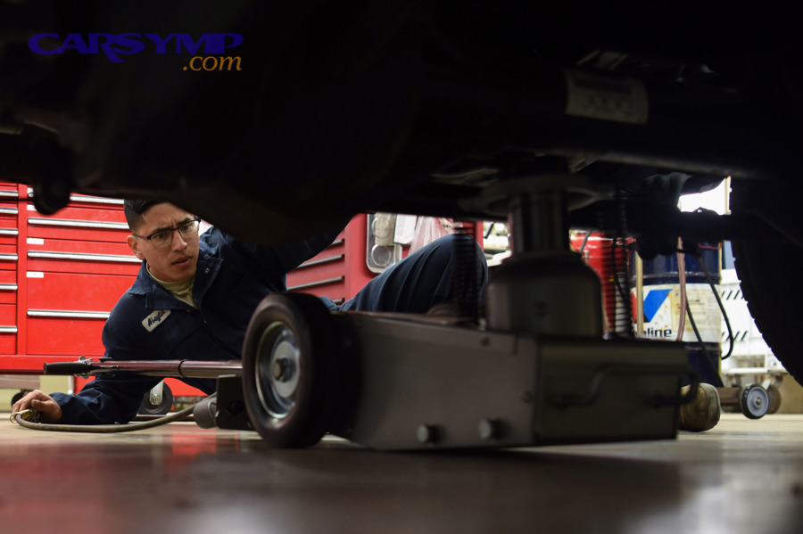 Person placing a jack underneath a vehicle during a tire change