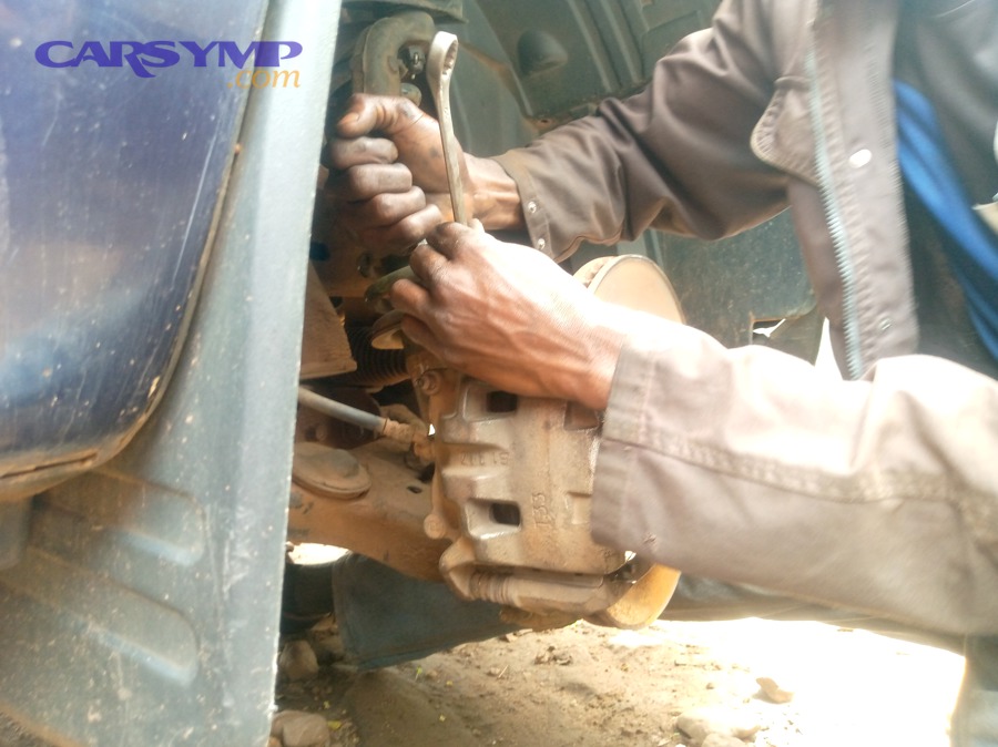 Mechanic working under a car, representing time and complexity that affect labor pricing