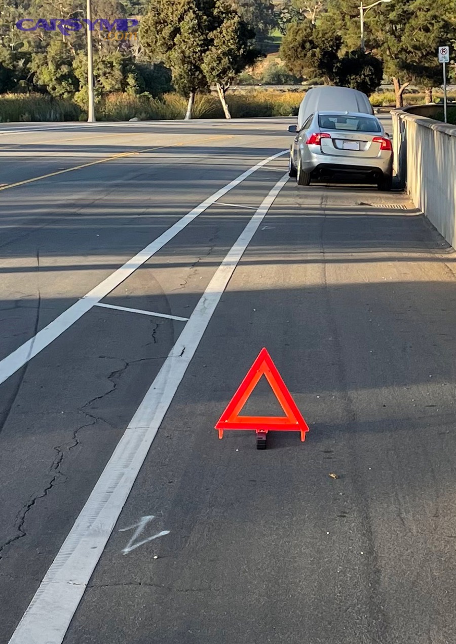 Broken down car pulled over with warning triangle set behind it