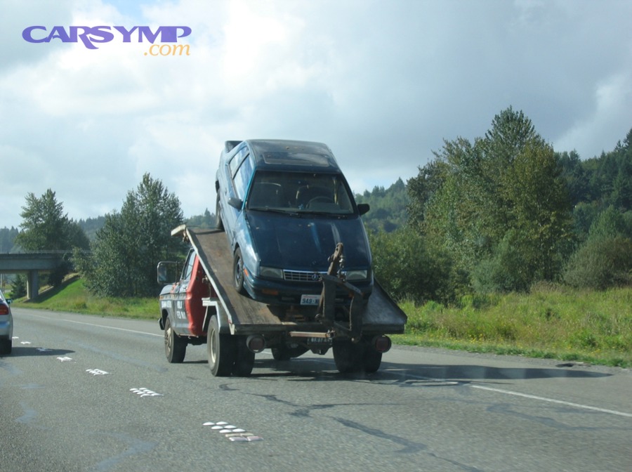 A car being towed by a tow truck on a roadway