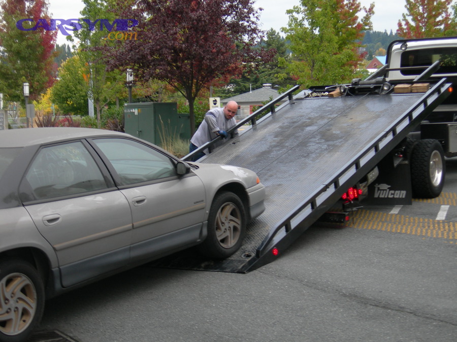 A car being loaded onto a flatbed tow truck during an emergency roadside situation
