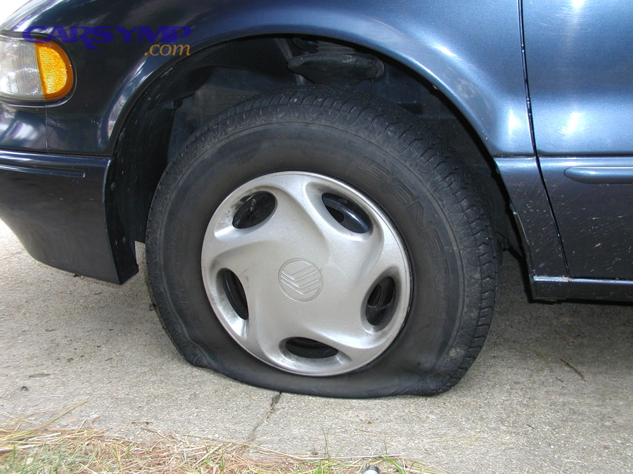A flat tire on a vehicle parked roadside