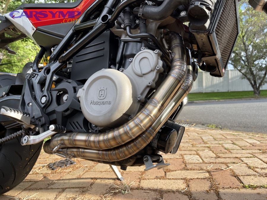 Stainless steel exhaust pipes on a motorcycle showing corrosion-resistant finish