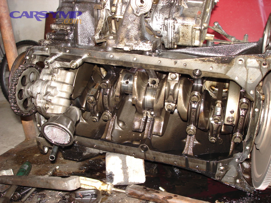 Engine with removed oil pan showing how oil can travel and drip from other areas