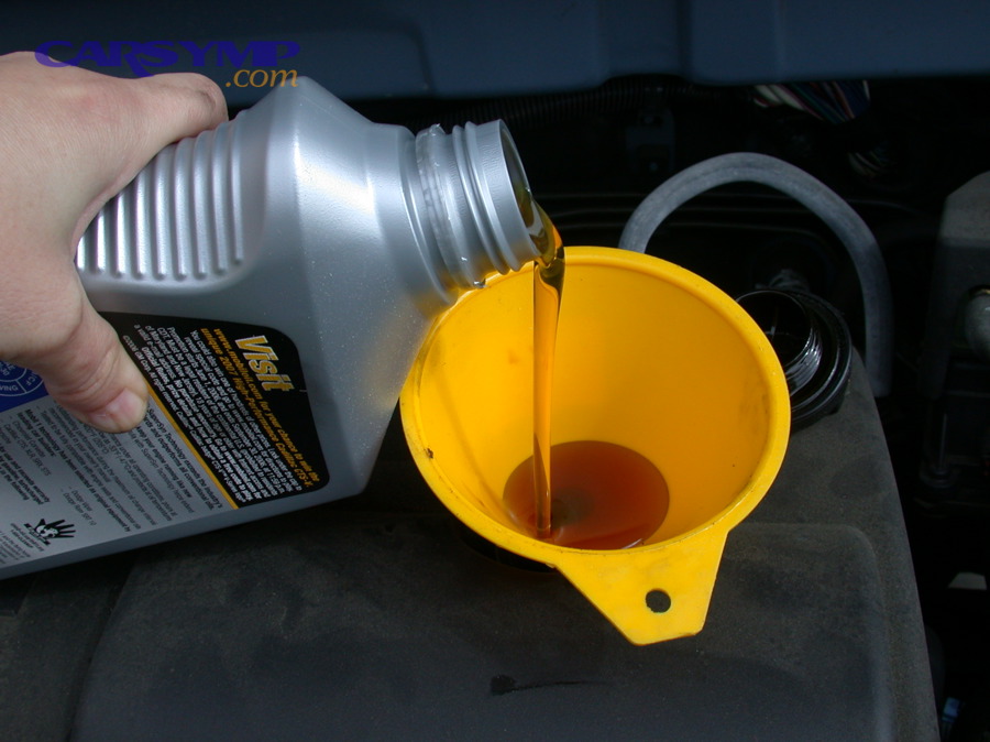 Refilling motor oil using a funnel during maintenance