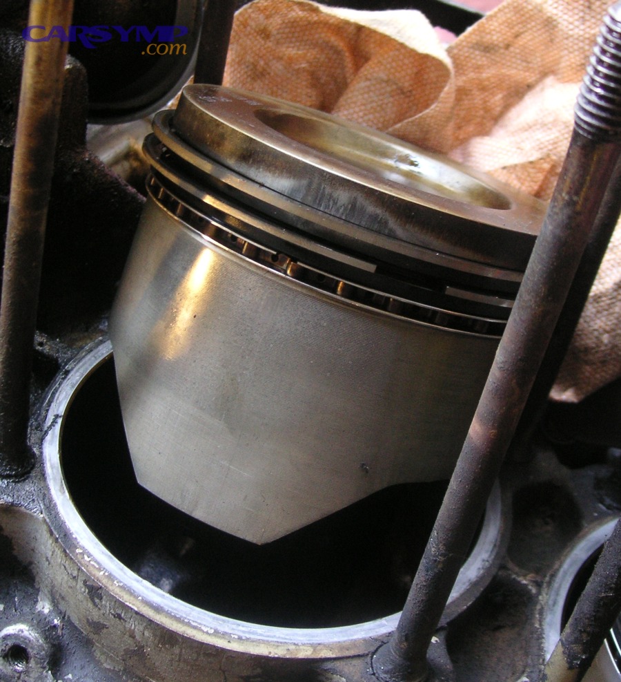 Piston with piston rings visible; ring wear can allow oil into combustion