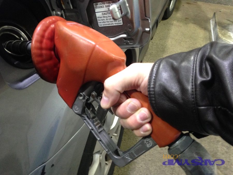 Driver refueling a car at a gas station using a fuel nozzle