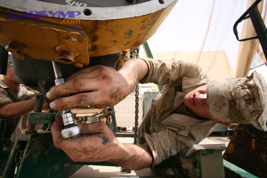 Mechanic working on an engine (example of common leak areas around gaskets and covers)