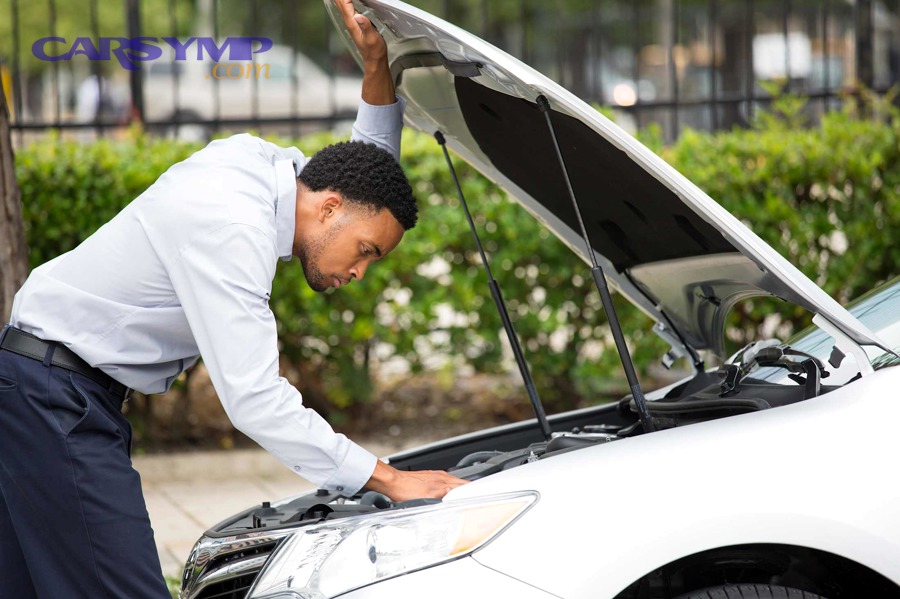Driver checking under hood after car overheats
