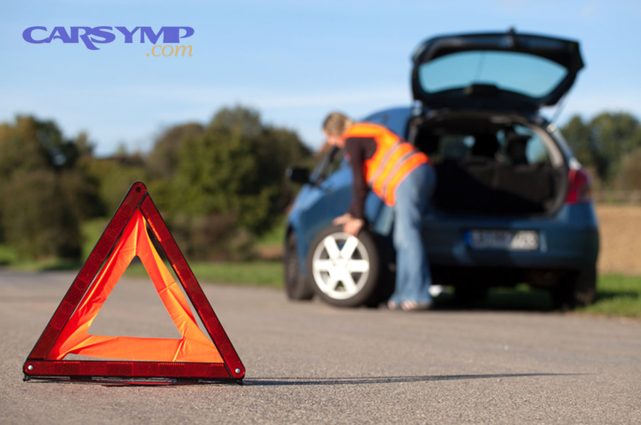 Person changing a tire using a lug wrench on a parked car