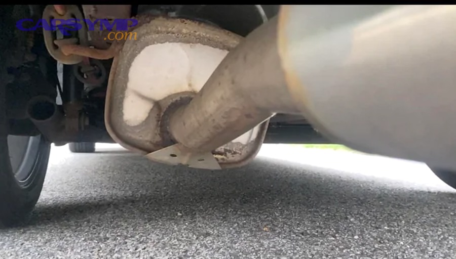 Mechanic inspecting underside of a car for an exhaust leak repair estimate