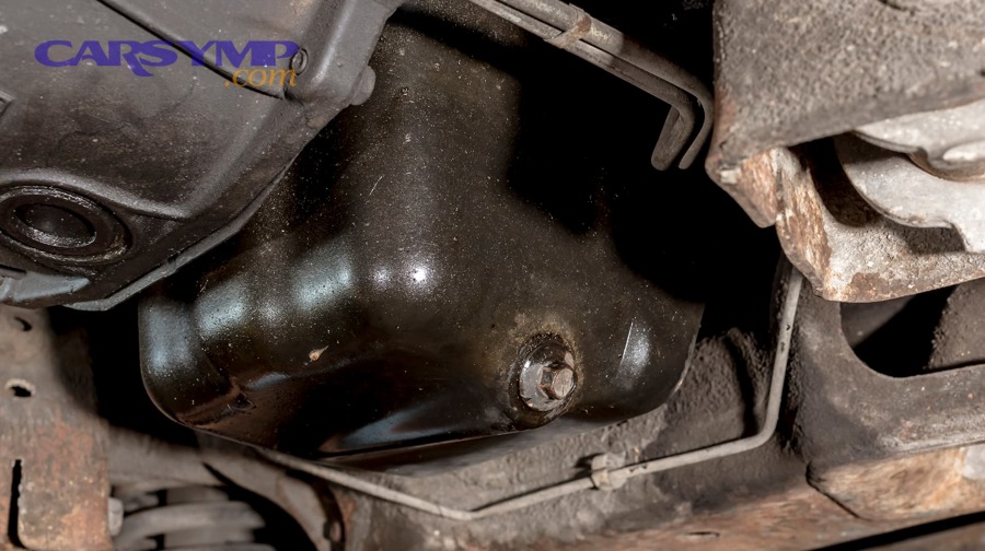 Engine oil leak leaving wet residue and grime on underside components