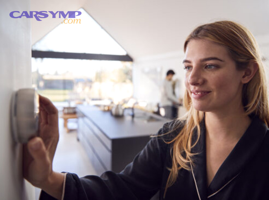 Person holding infrared thermometer checking room temperature near wall-mounted thermostat