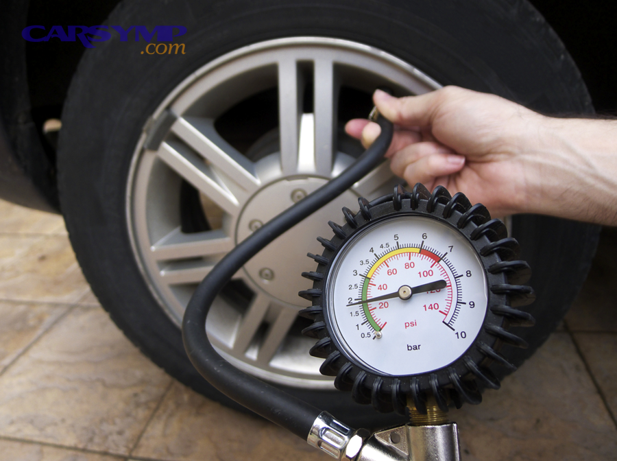 tire pressure gauge showing PSI reading on a car tire valve stem