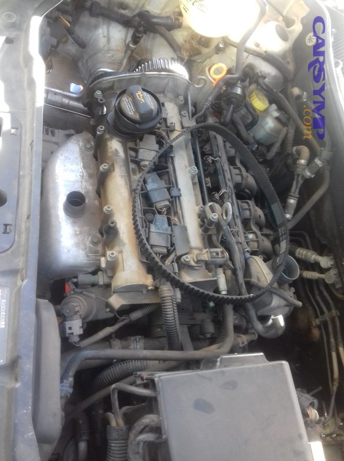 Engine bay view during water pump replacement on a compact car