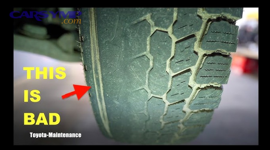 Mechanic inspecting wheel alignment and suspension to diagnose tire wear