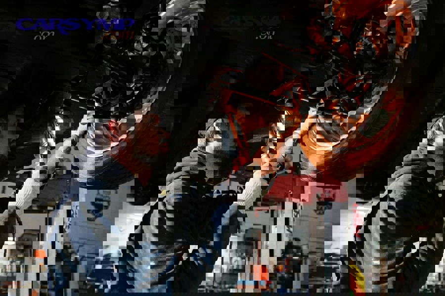 Mechanic inspecting engine belt and cooling system components