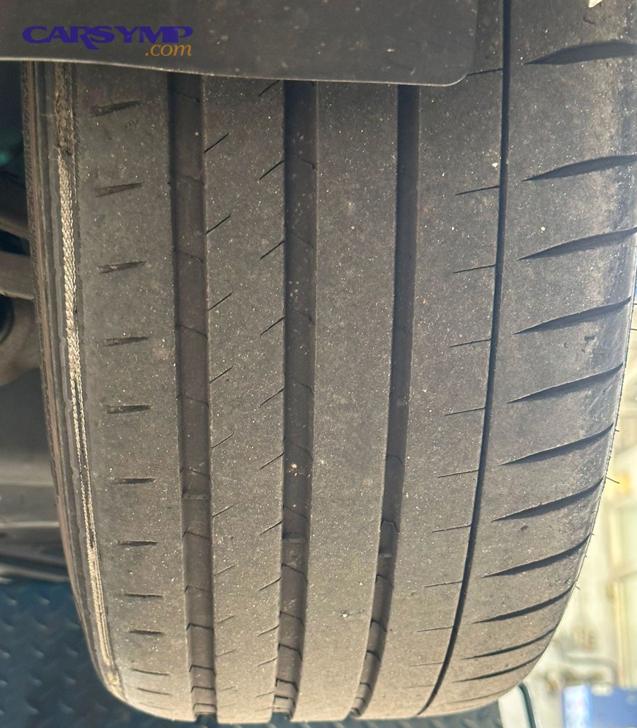 Technician inspecting tire wear on a vehicle