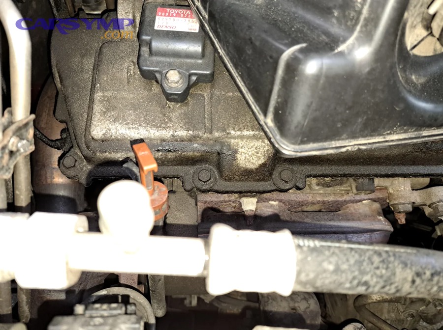 Mechanic inspecting engine for valve cover gasket leak symptoms